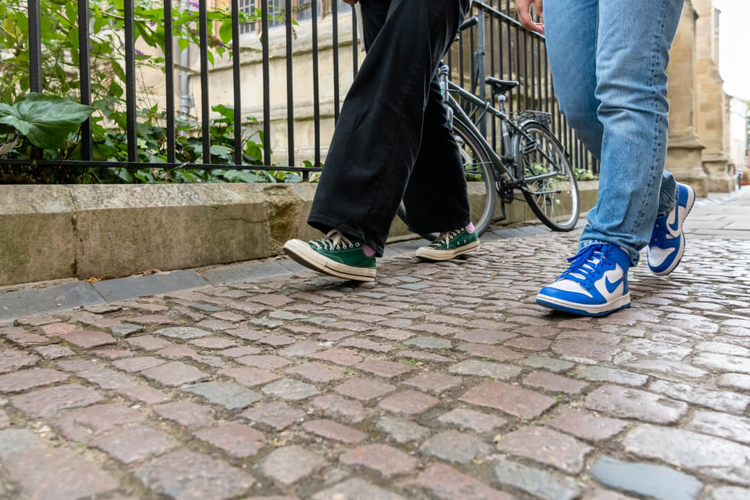 Two Oxford Scholastica students walking on a cobbled street.
