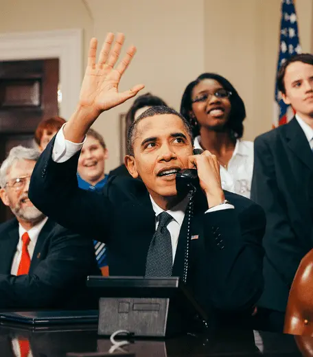 Photograph of Barack Obama on the phone and waving