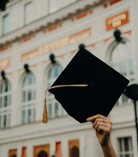 Hand holding up a graduation mortarboard