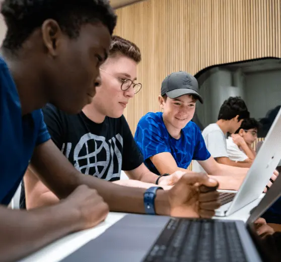 students sat working on their laptops and smiling together