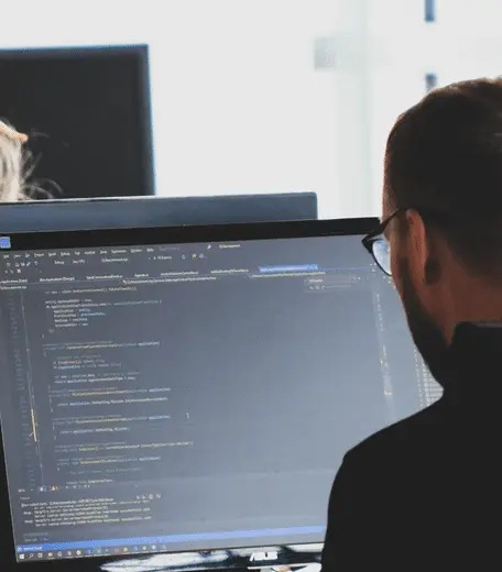 man working on large computer screen of code