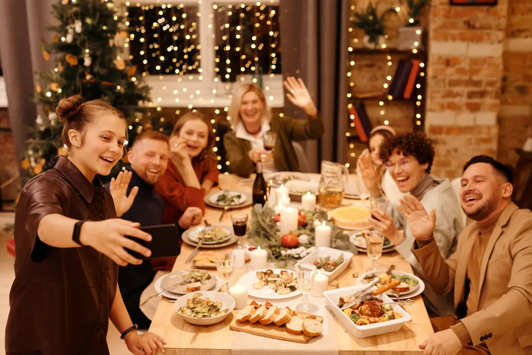 Large family gathering around a dining table, taking a selfie over Christmas dinner