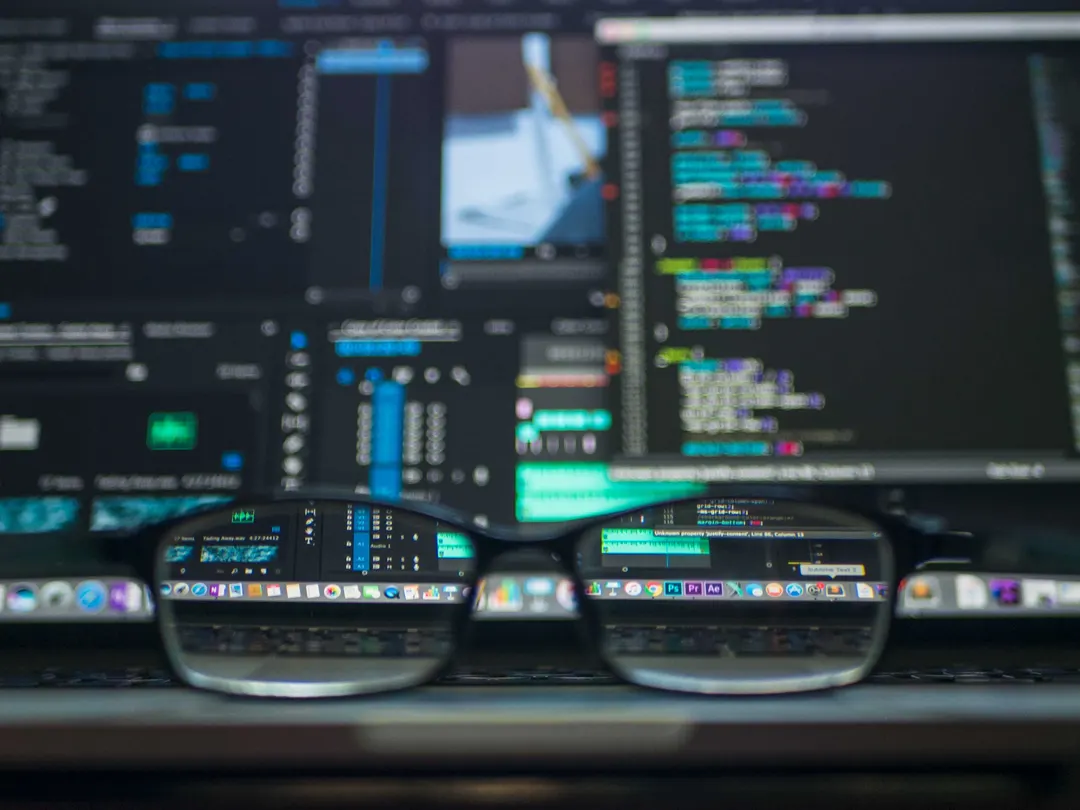 Eye glasses resting on an open laptop, showing code in the background