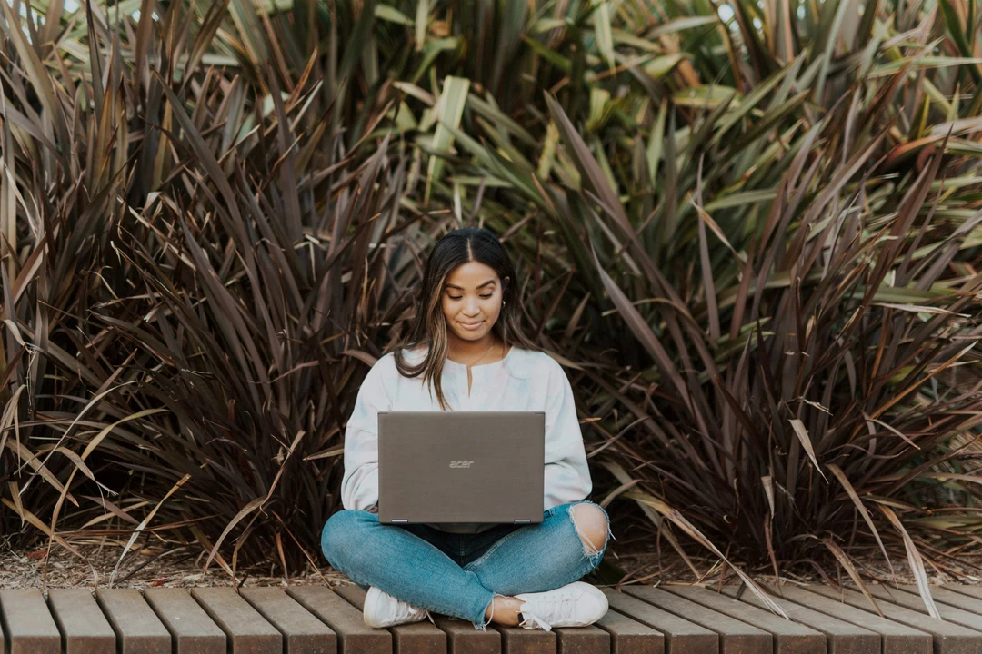 Student sitting cross-legged, working on their laptop